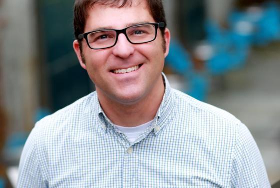photo of Dr Andrew Beck smiling wearing glasses and a light blue shirt